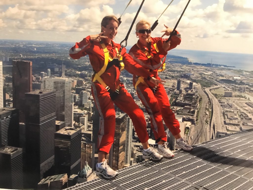 two women in jumpsuits on a platform overlooking Toronto 