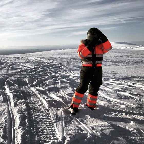 person in an orange snowmobile suite and black helmet