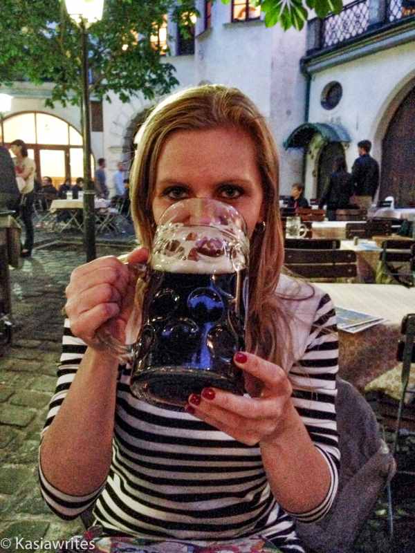 woman drinking dark beer out of a glass stein