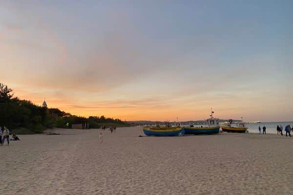 Sun setting on a beach in Sopot with boats on the shore