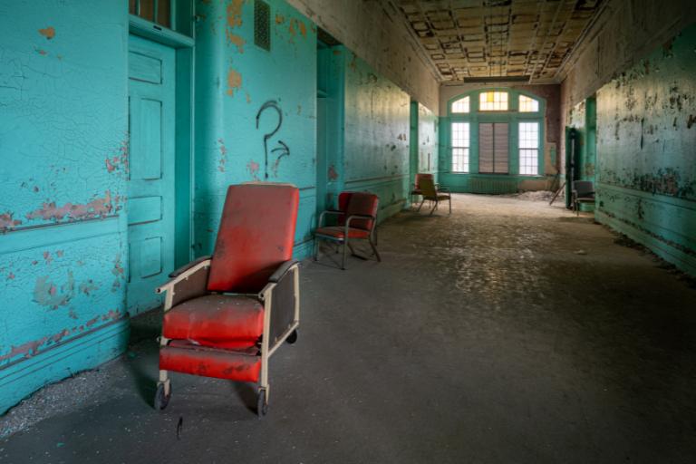 a red chair in a hallway of an abandoned building